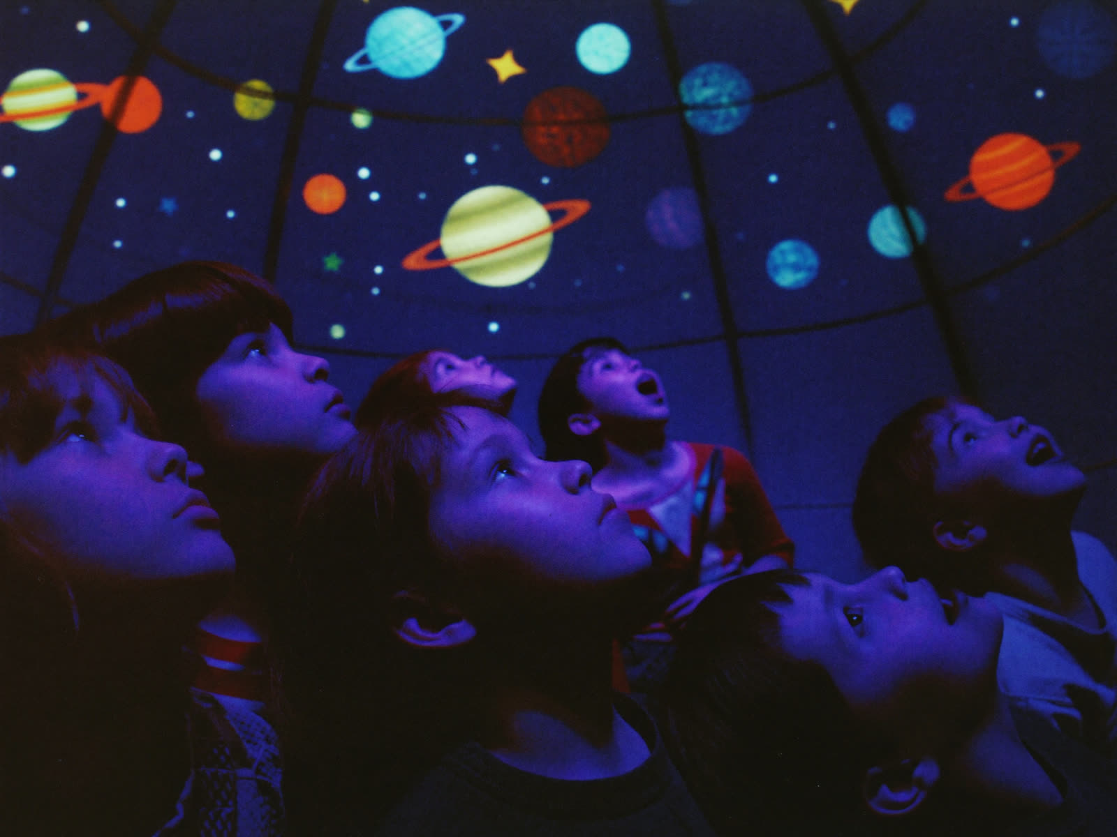 Children gazing up at glowing planets under the Space Loft star dome
