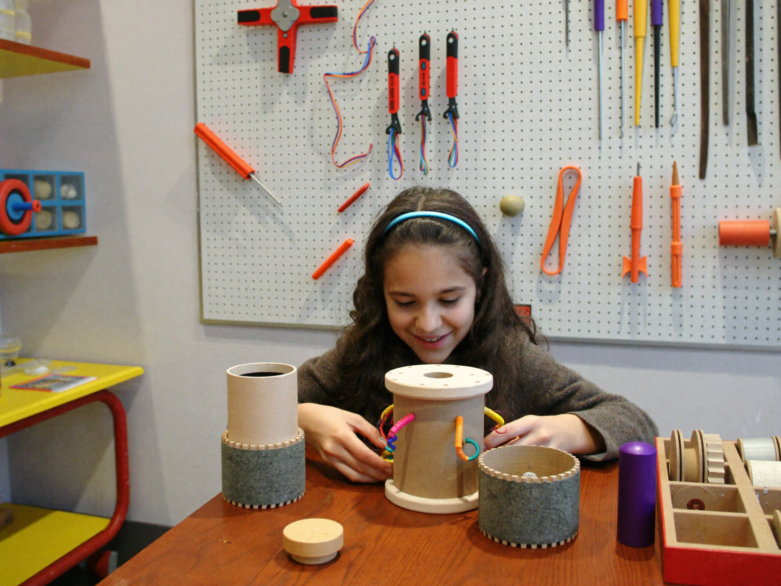 A young builder assembling a gear contraption at the Tinker Lab workbench
