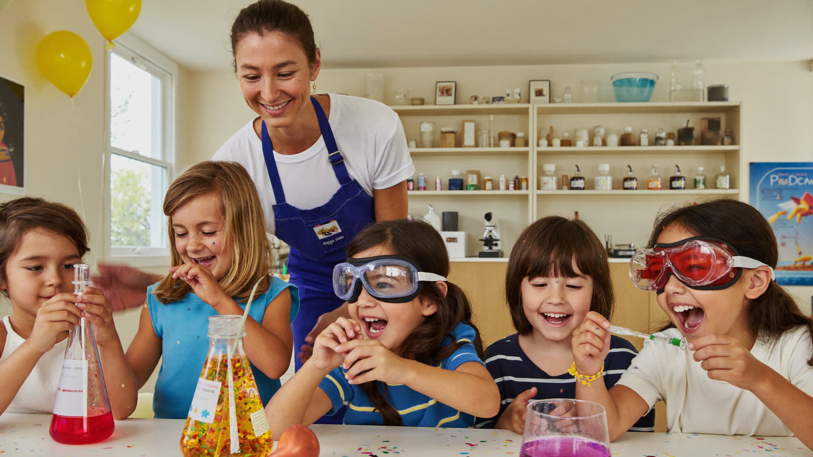 Kids in safety goggles cheering at a fizzing science experiment during a Curio birthday party
